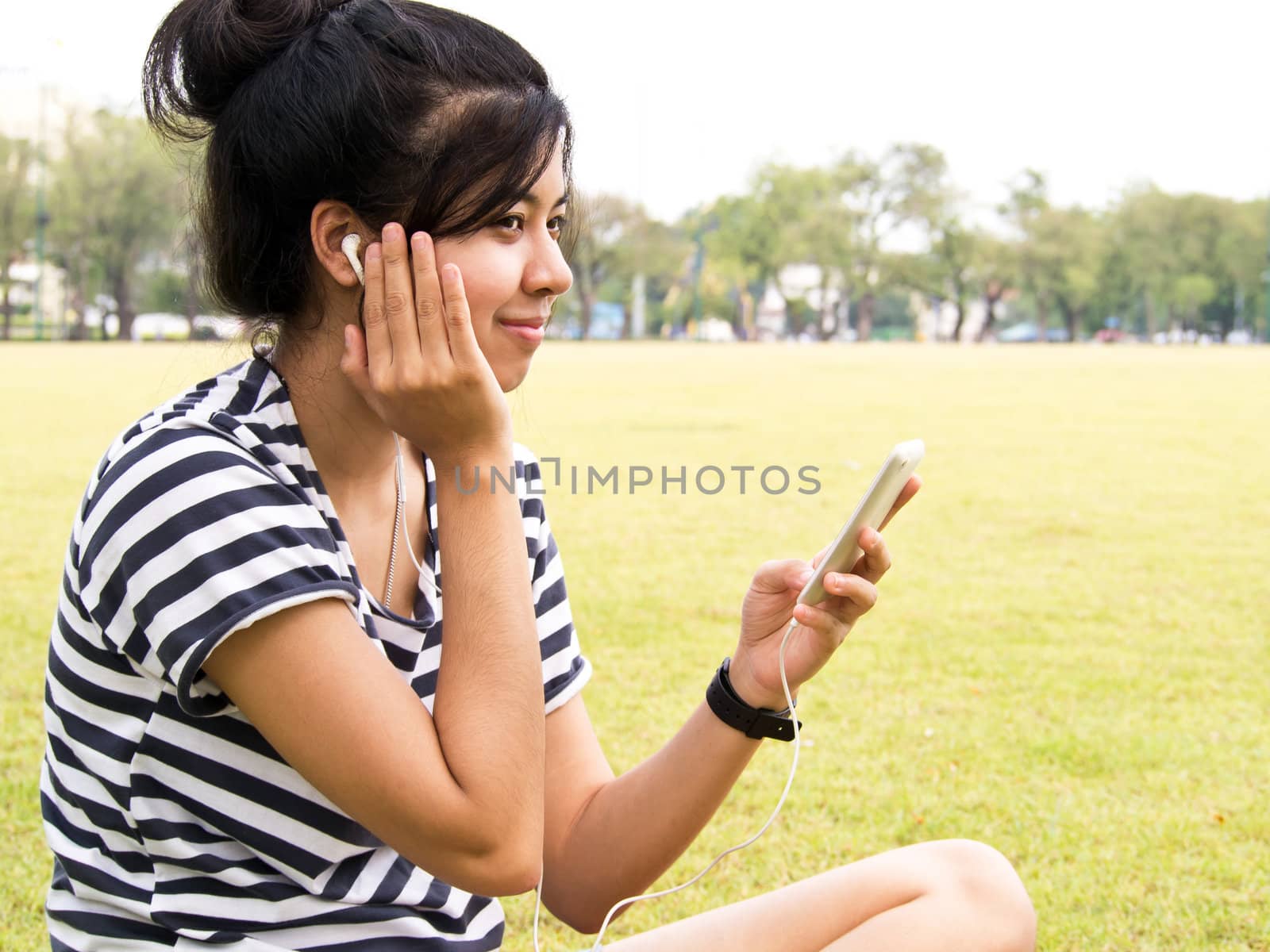A young girl with headphones outdoors. Listening music  by siraanamwong