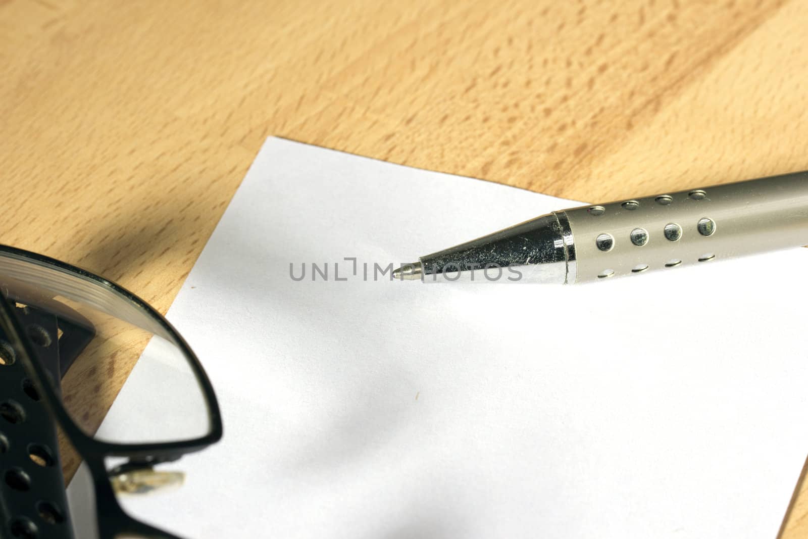 White sheet of paper and a silver pen at work desk