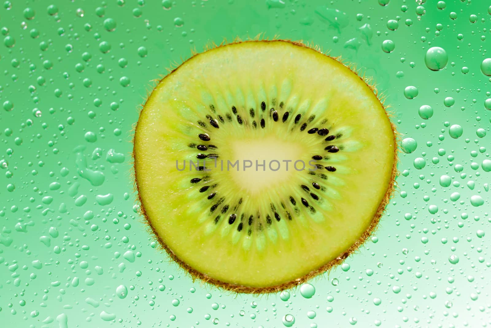 Slice of kiwi with drop on green background