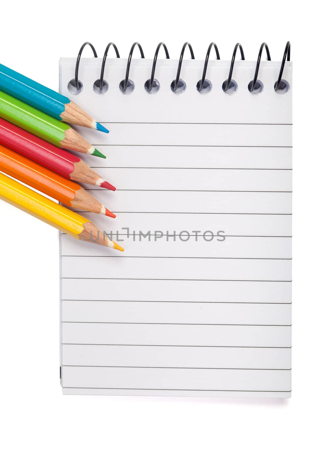 A vivid image with various colored pencils such as yellow, orange, red and blue on a notebook.