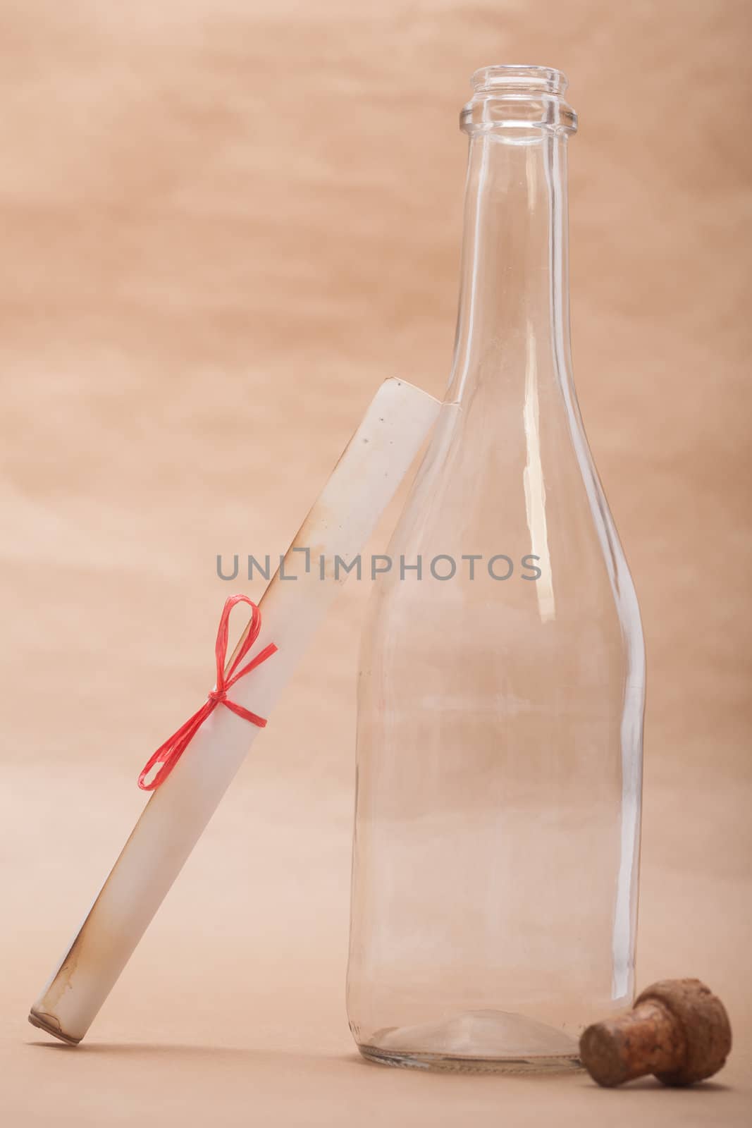 A message next to a glass bottle, isolated on a sand color background, in a studio shot.