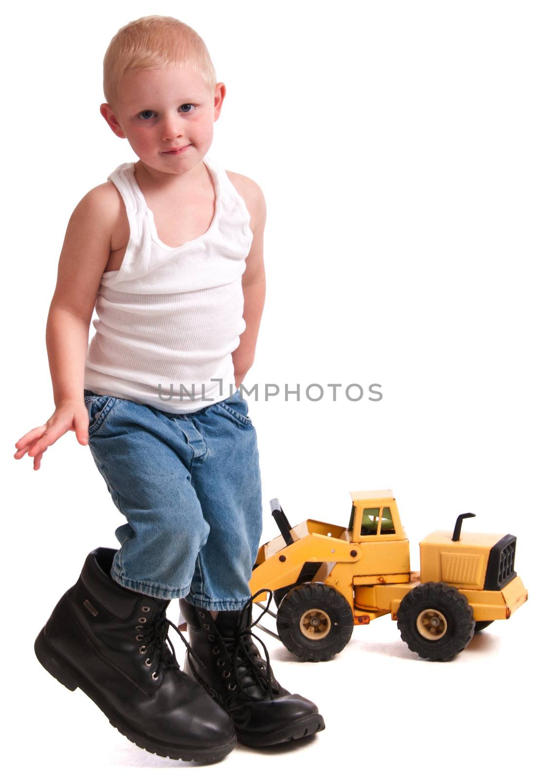 Cute little boy with daddy's boots playing with a toy.