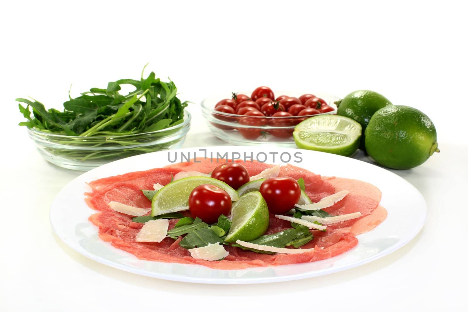 a plate of carpaccio with parmesan, rocket and lime