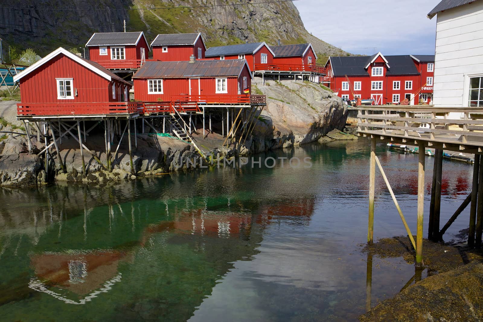 Typical red rorbu fishing huts on Lofoten islands in Norway reflecting in fjord