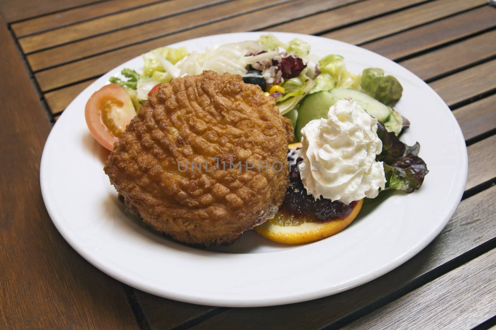 Fried camembert with garnish on a white plate