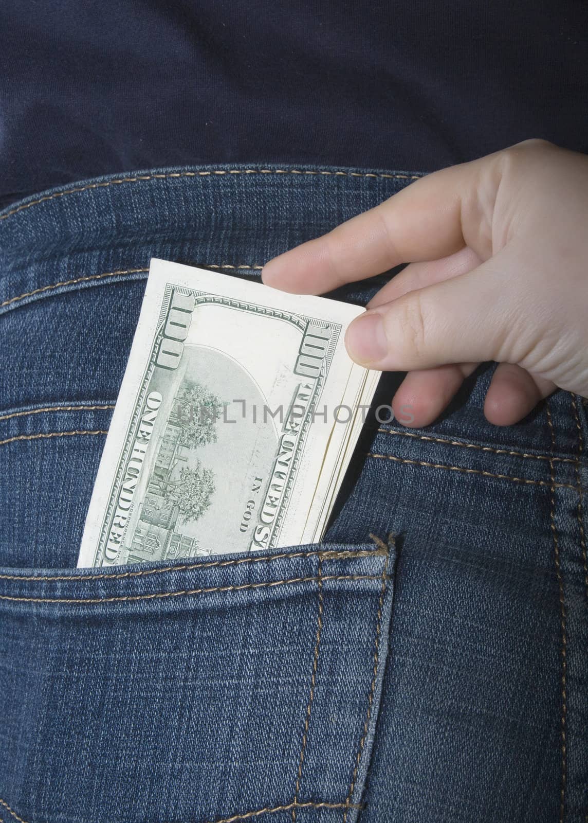 Bundle of dollars in a jeans rear pocket and a hand pulling them out