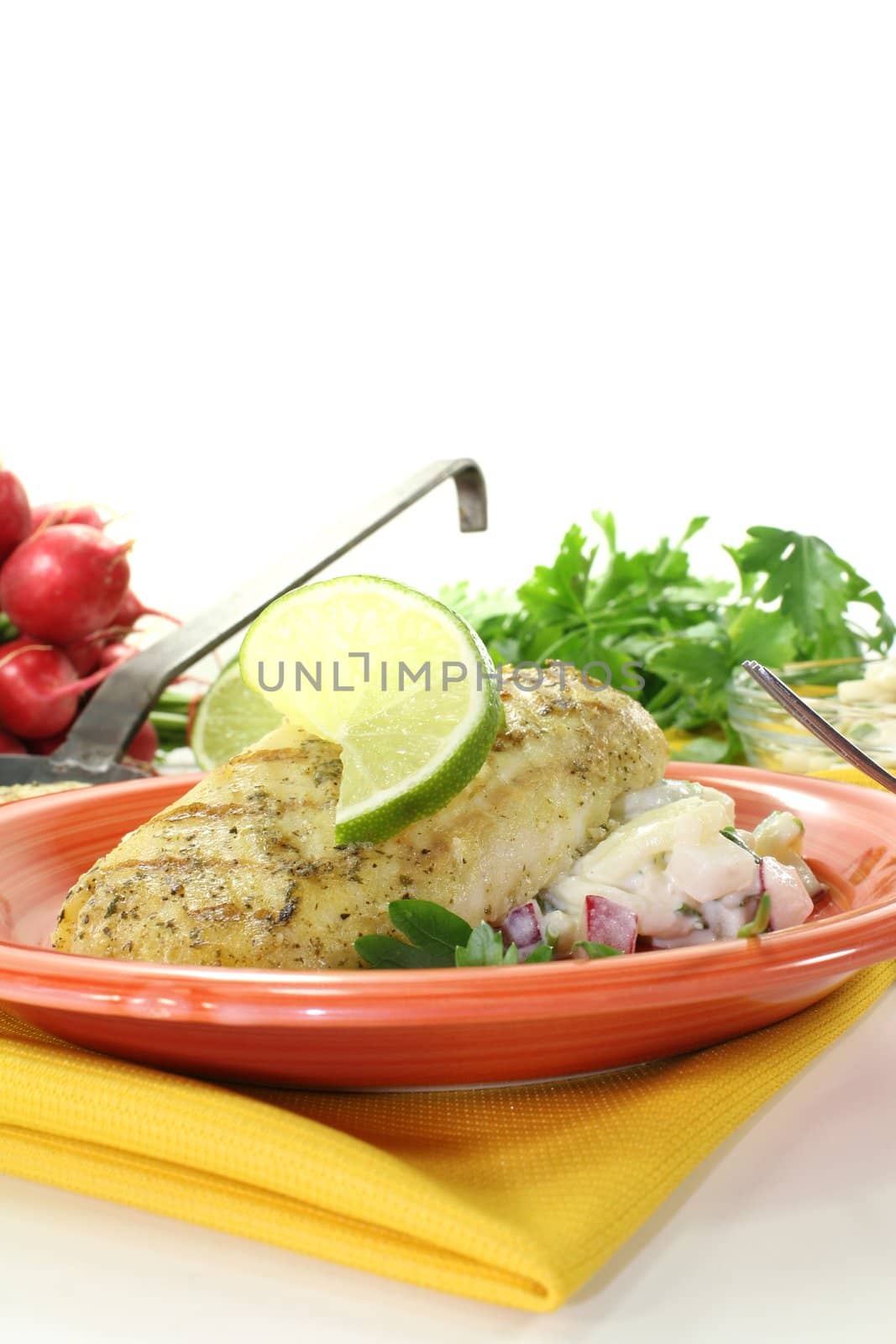 Hake with lemon slice, parsley, chives and potato salad on a light background