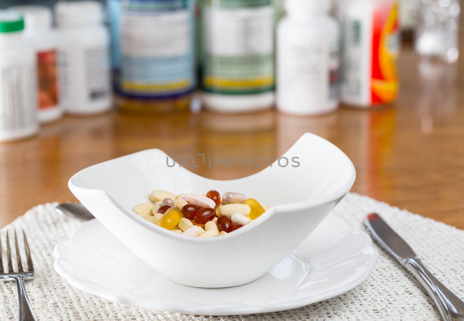 Vitamins in bowl of tablets for breakfast in kitchen with rows of bottles in background