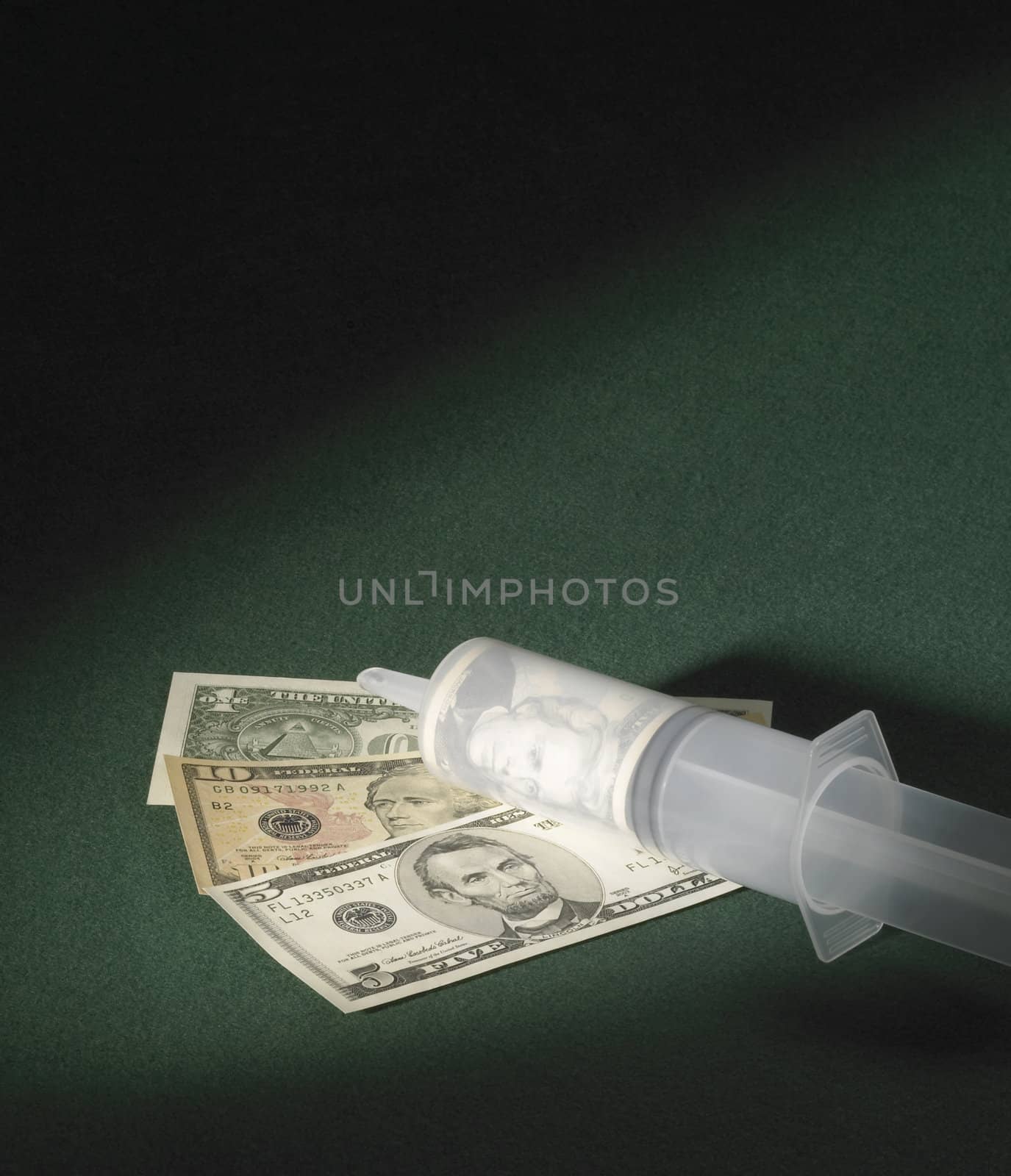 symbolic picture showing a big syringe and dollar banknotes on green felt