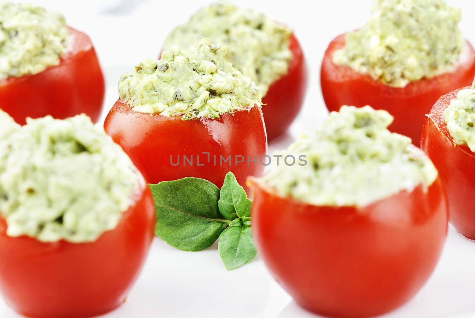 Stuffed Tomatoes filled with a pesto and avocado mixture. Extreme shallow depth of field with selective focus on center tomato.