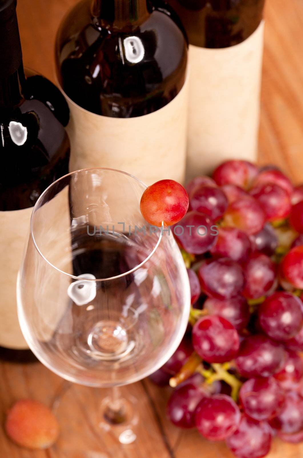 macro shot of one red grapes berry in glass. on wine bottle background