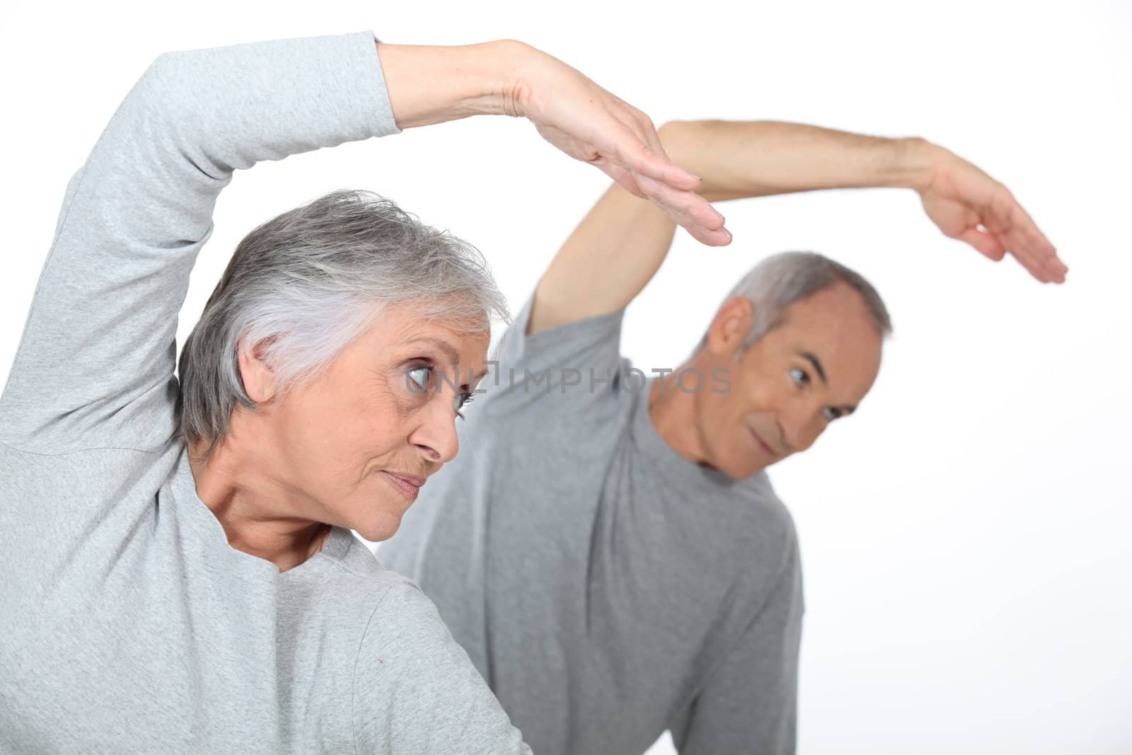 Senior couple stretching in the gym by phovoir