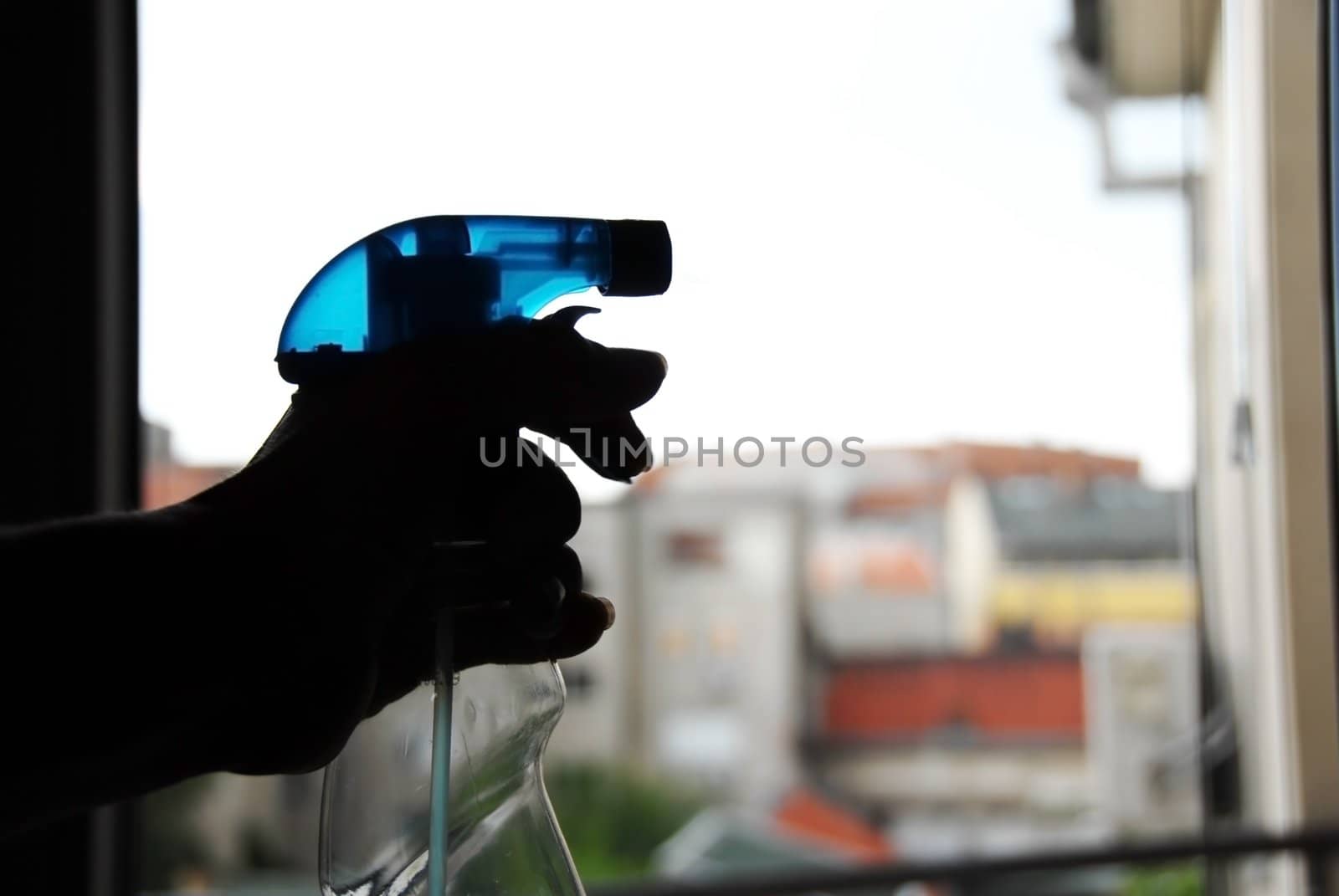 hand holding blue plastic on window cleaning a glass