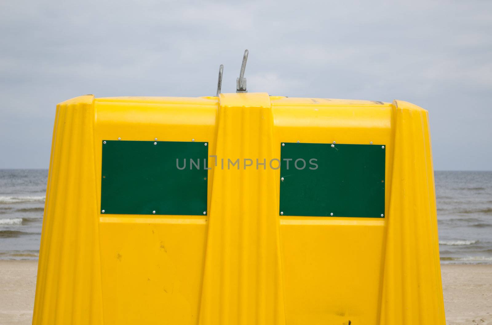 Closeup of yellow waste bin container on sea beach.
