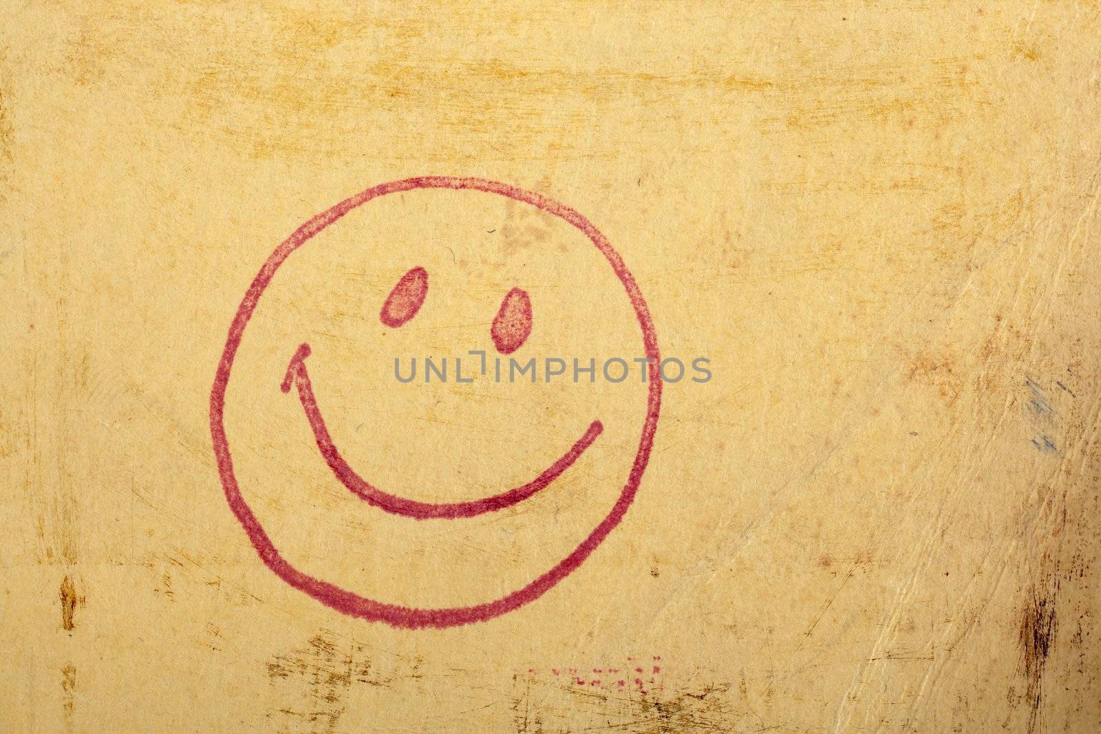 Photo of a vintage happy face stamp on old scratched worn paper.