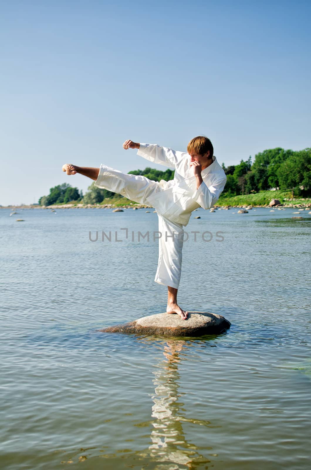 Man in kimono training on the rock in the sea