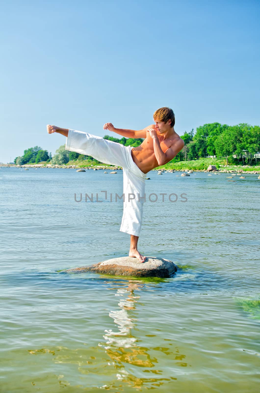 Man in kimono training on the rock in the sea