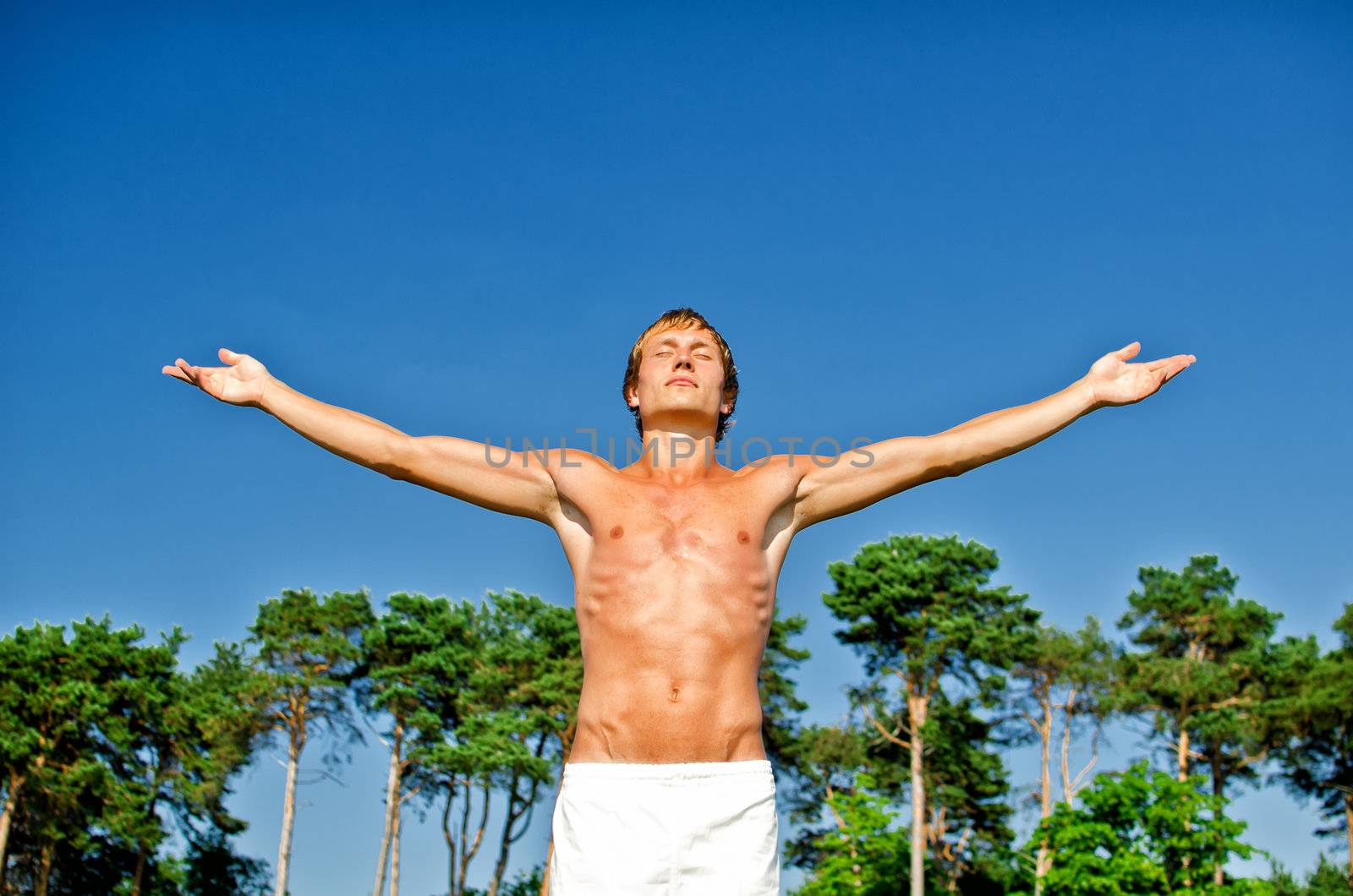 Young man doing meditation exercises on sky background