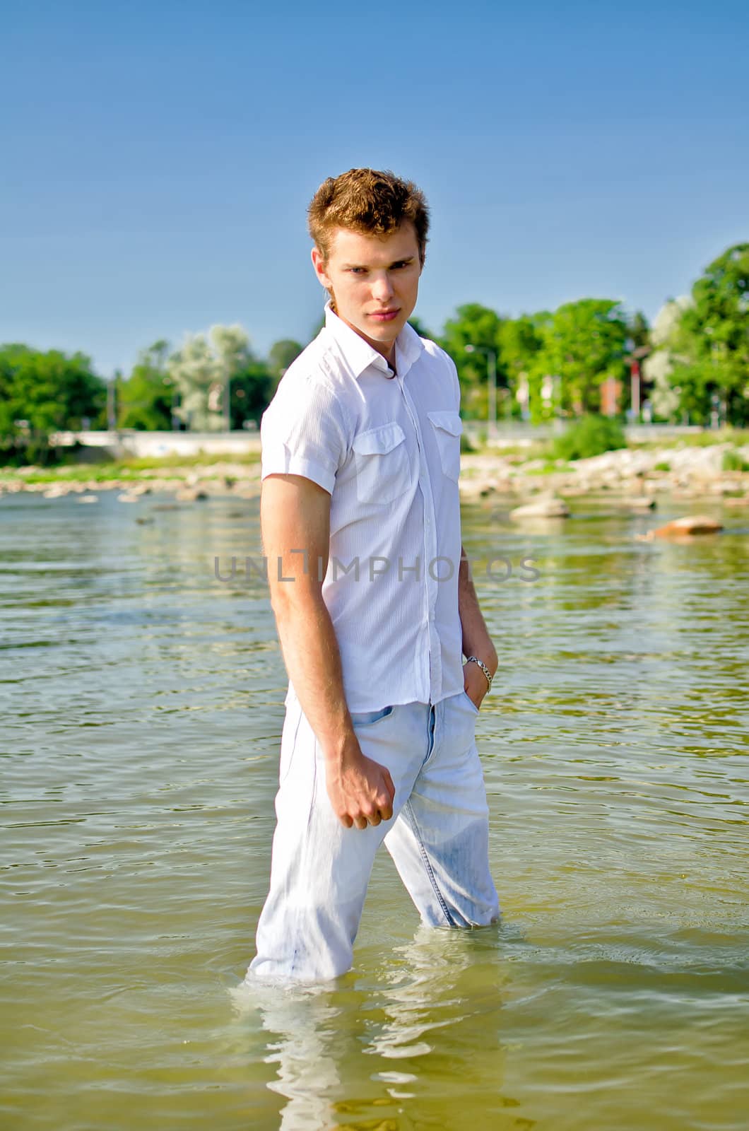 Handsome young guy standing in the sea in jeans