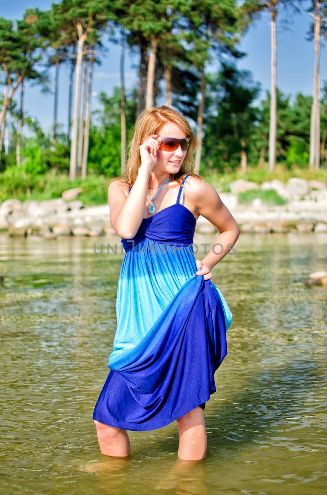 Pretty woman in a long dress posing in the sea