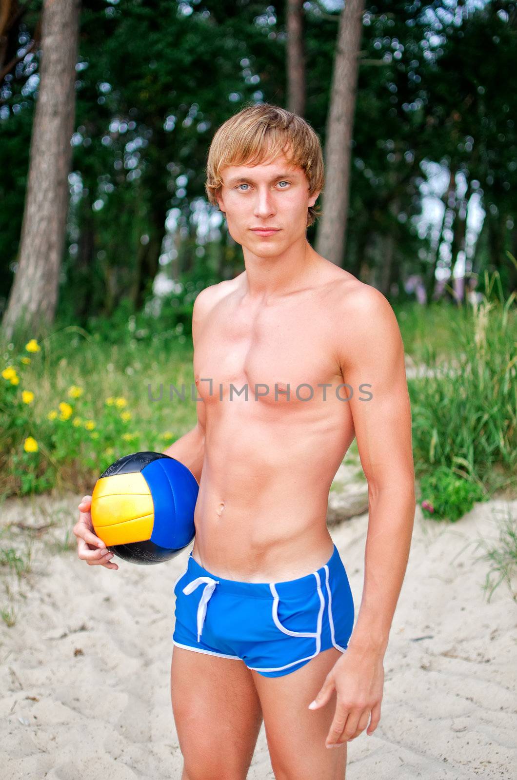 Young man posing with the ball on the beach