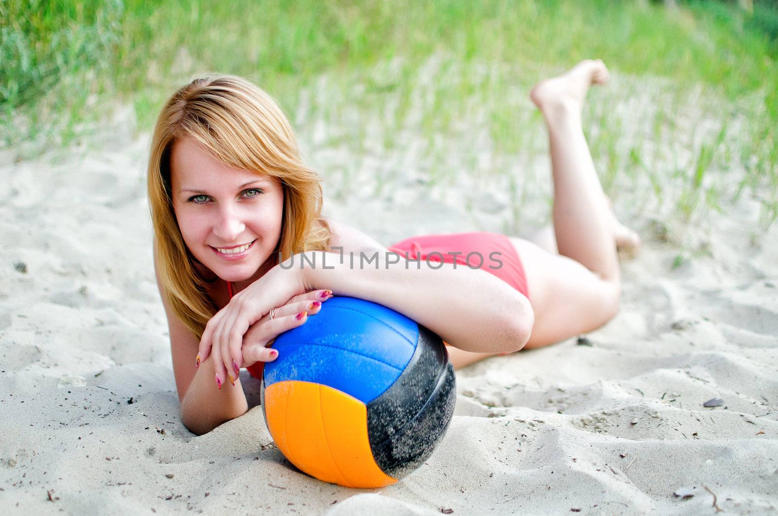 Pretty woman with the ball lying on the beach 