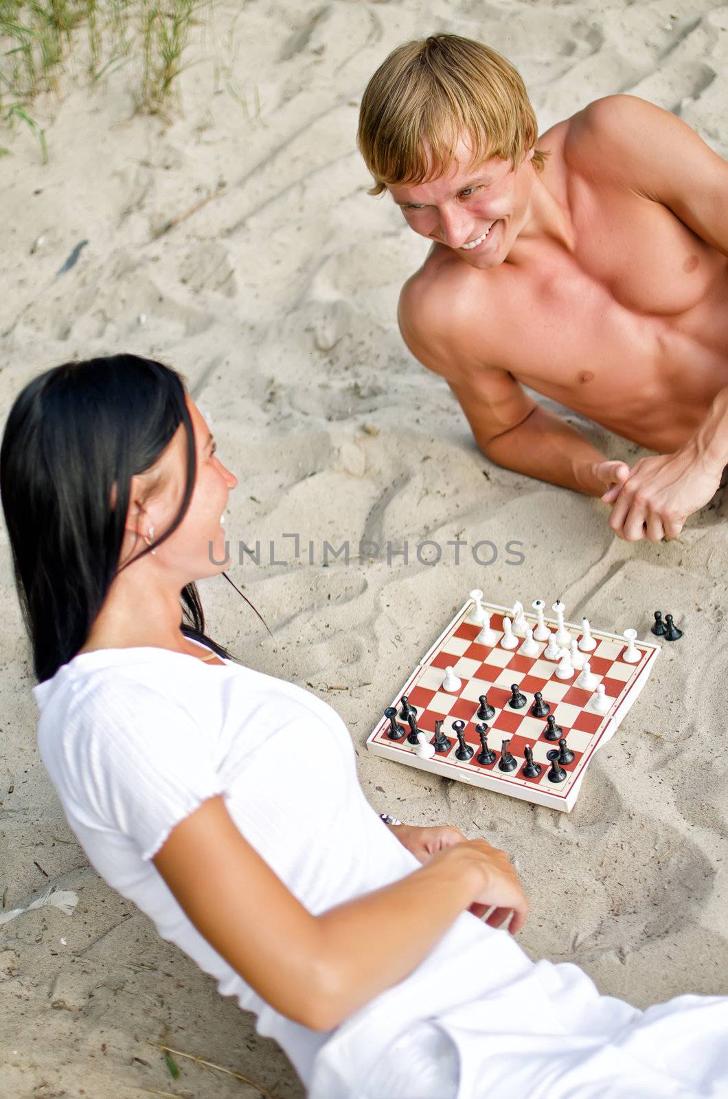Young couple playing chess on the beach