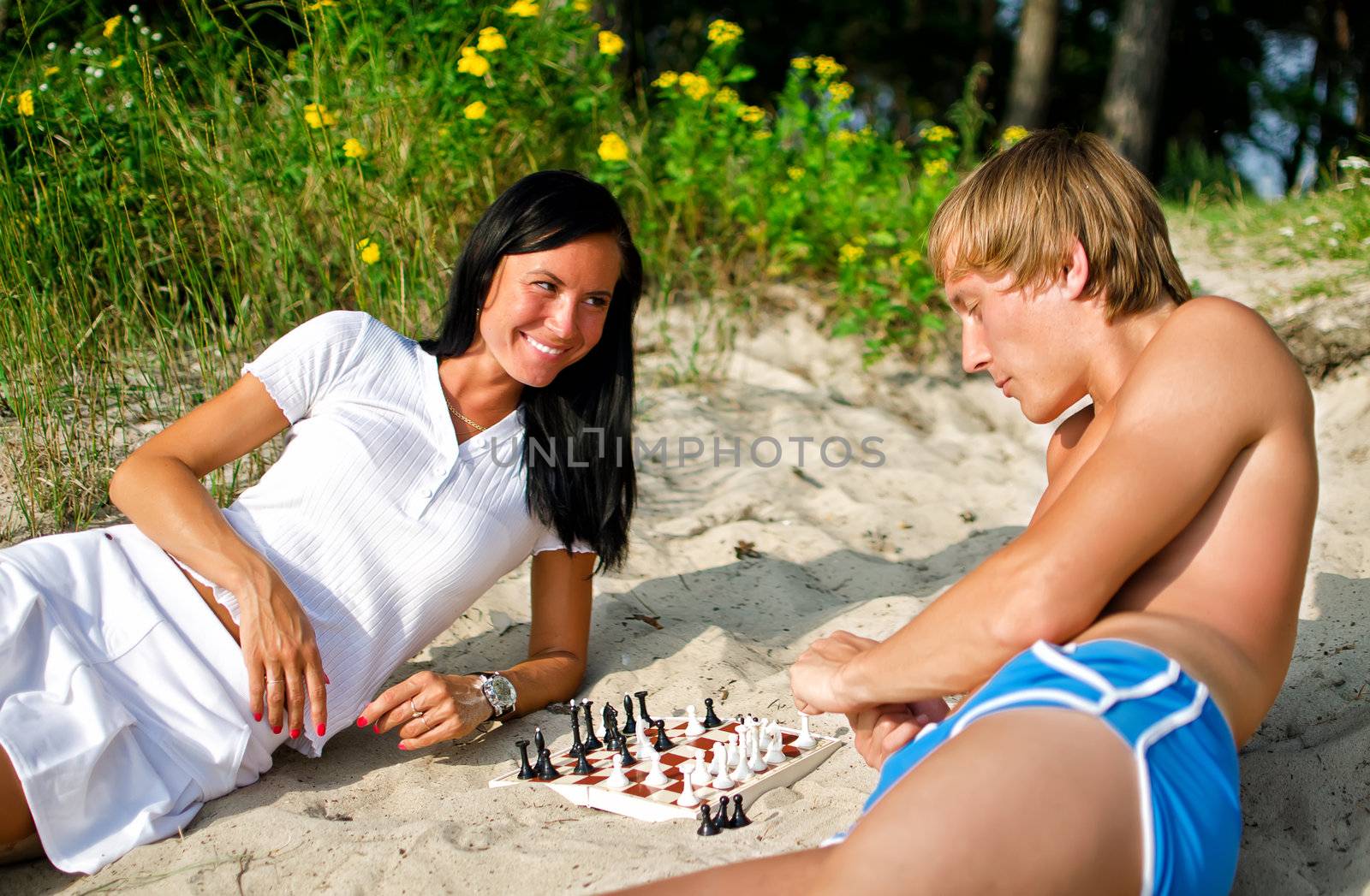 Young couple playing chess on the beach by dmitrimaruta