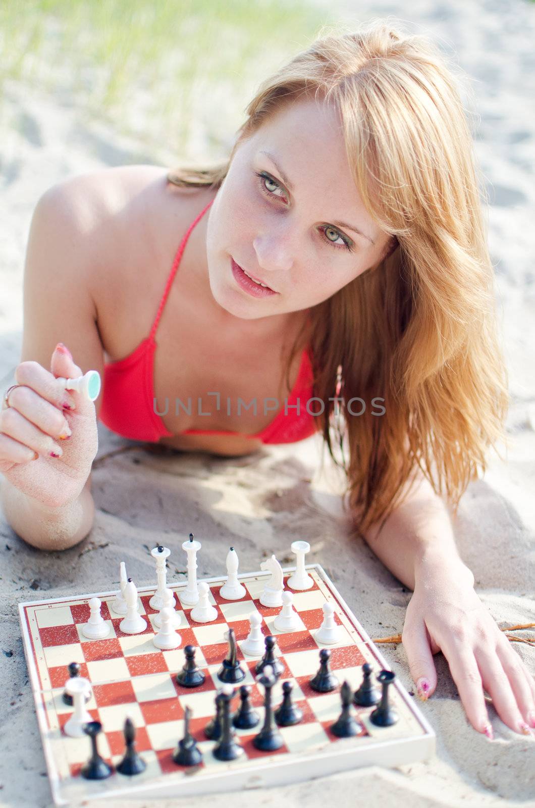 Portrait of pretty woman playing chess on the beach