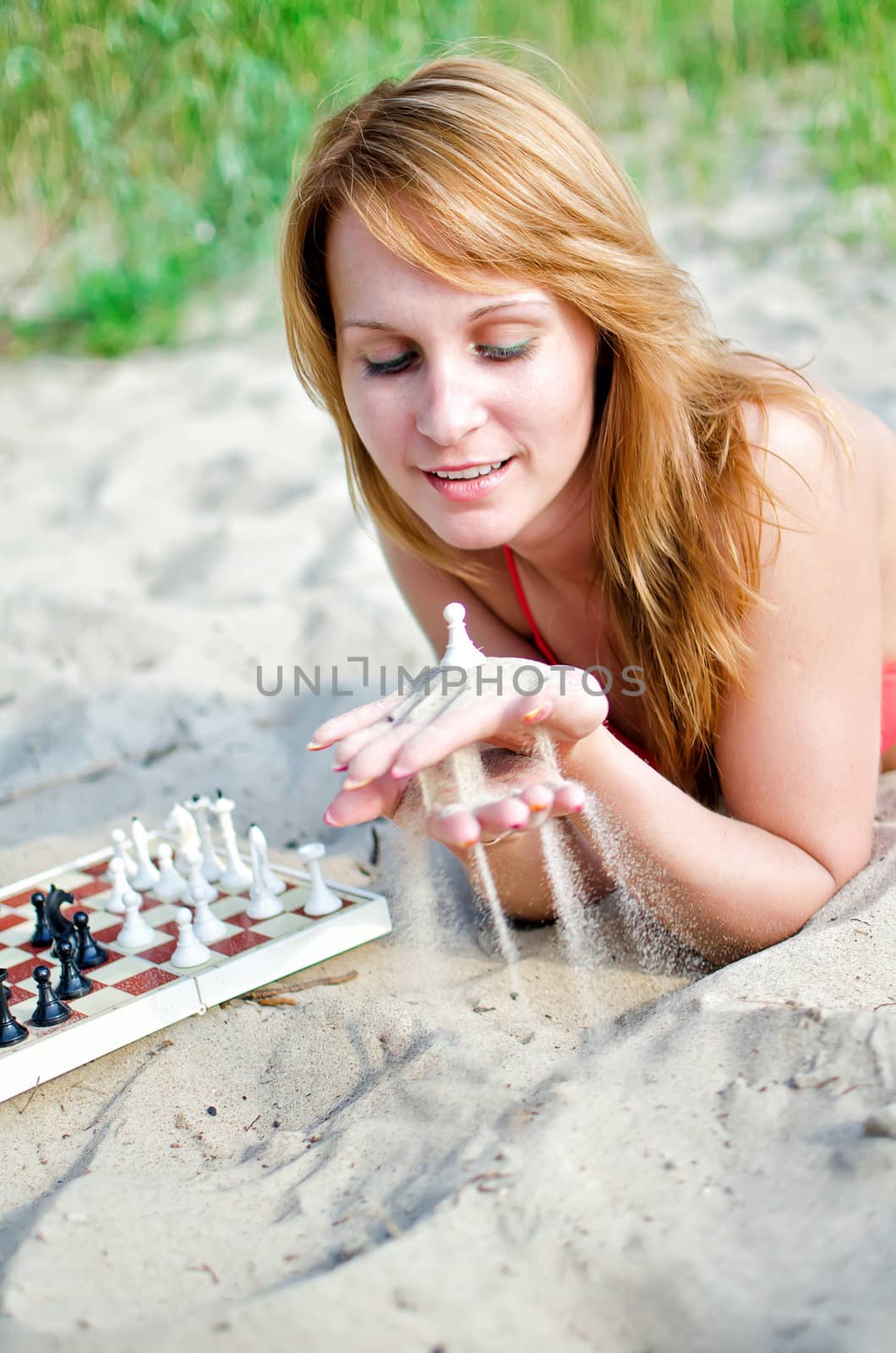 Portrait of pretty woman playing chess on the beach by dmitrimaruta