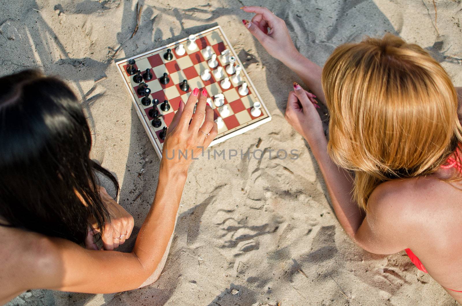 Two girls playing chess on the beach