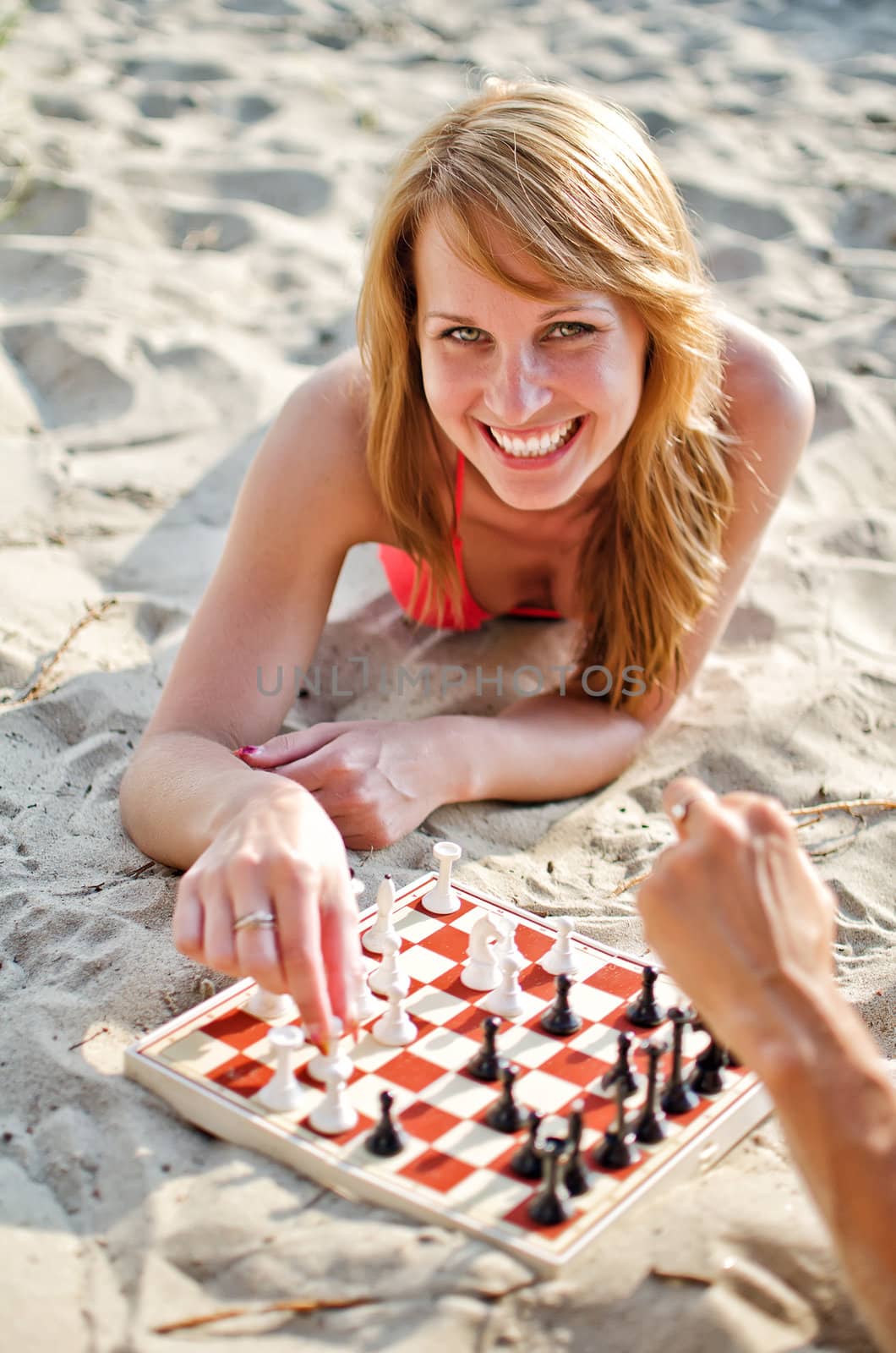 Portrait of pretty woman playing chess on the beach