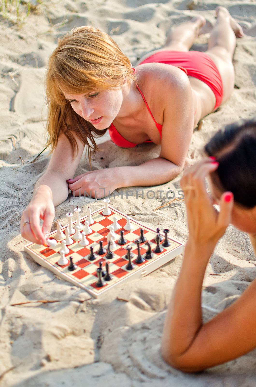 Two girls playing chess on the beach by dmitrimaruta