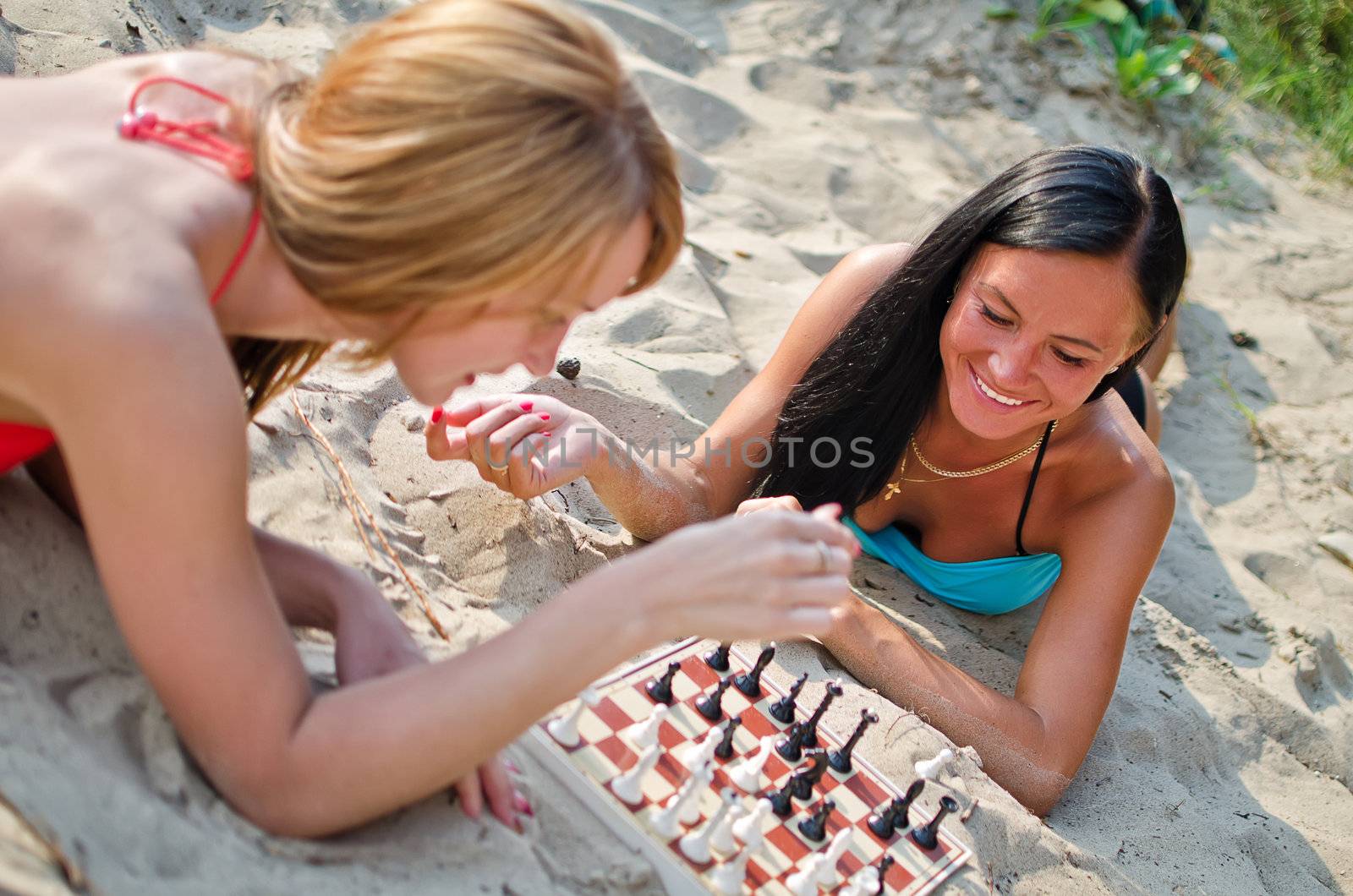 Two girls playing chess on the beach