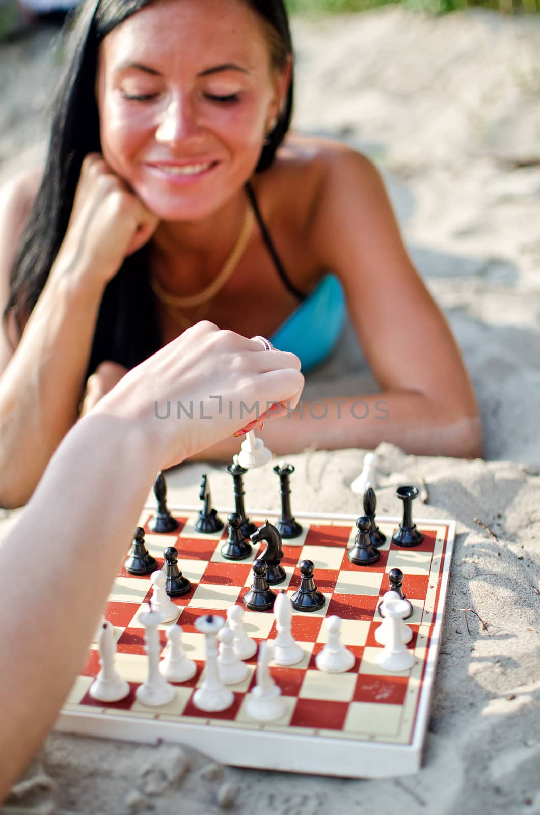 Portrait of pretty woman playing chess on the beach