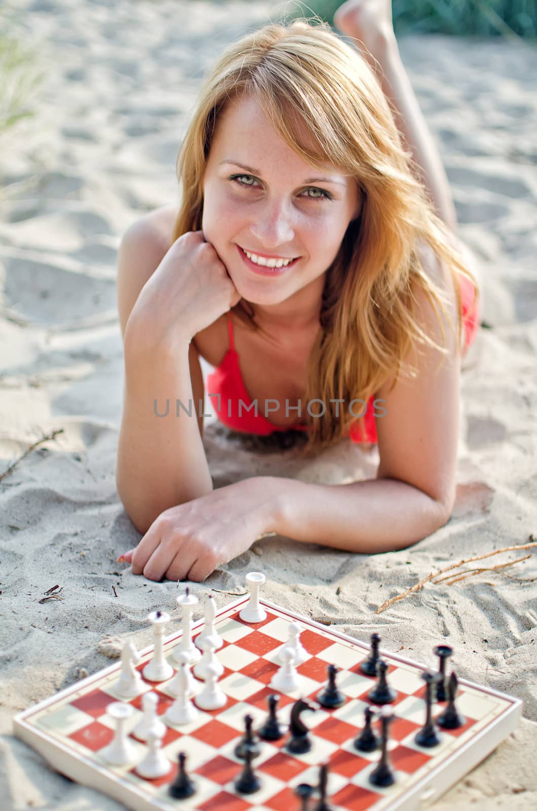 Portrait of pretty woman playing chess on the beach
