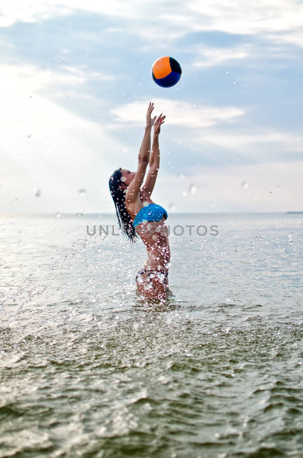 Young woman playing volleyball in the sea by dmitrimaruta