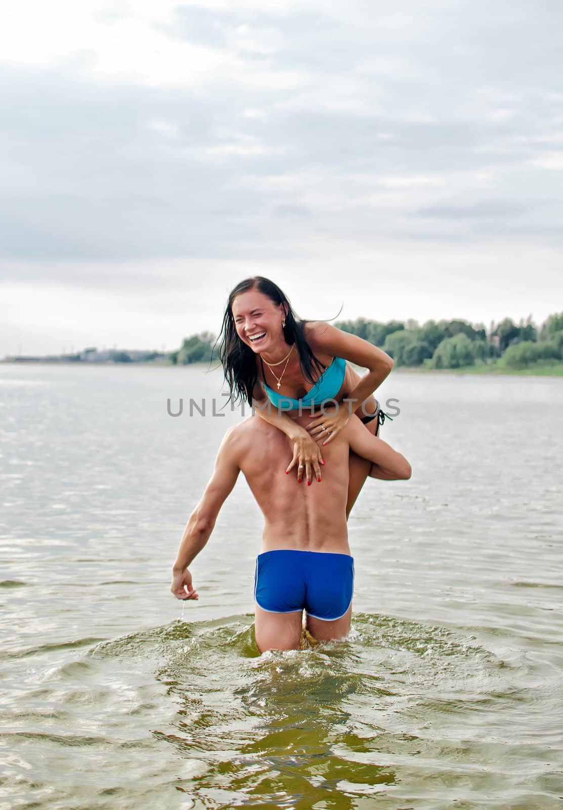Man carrying woman on shoulder in the sea by dmitrimaruta