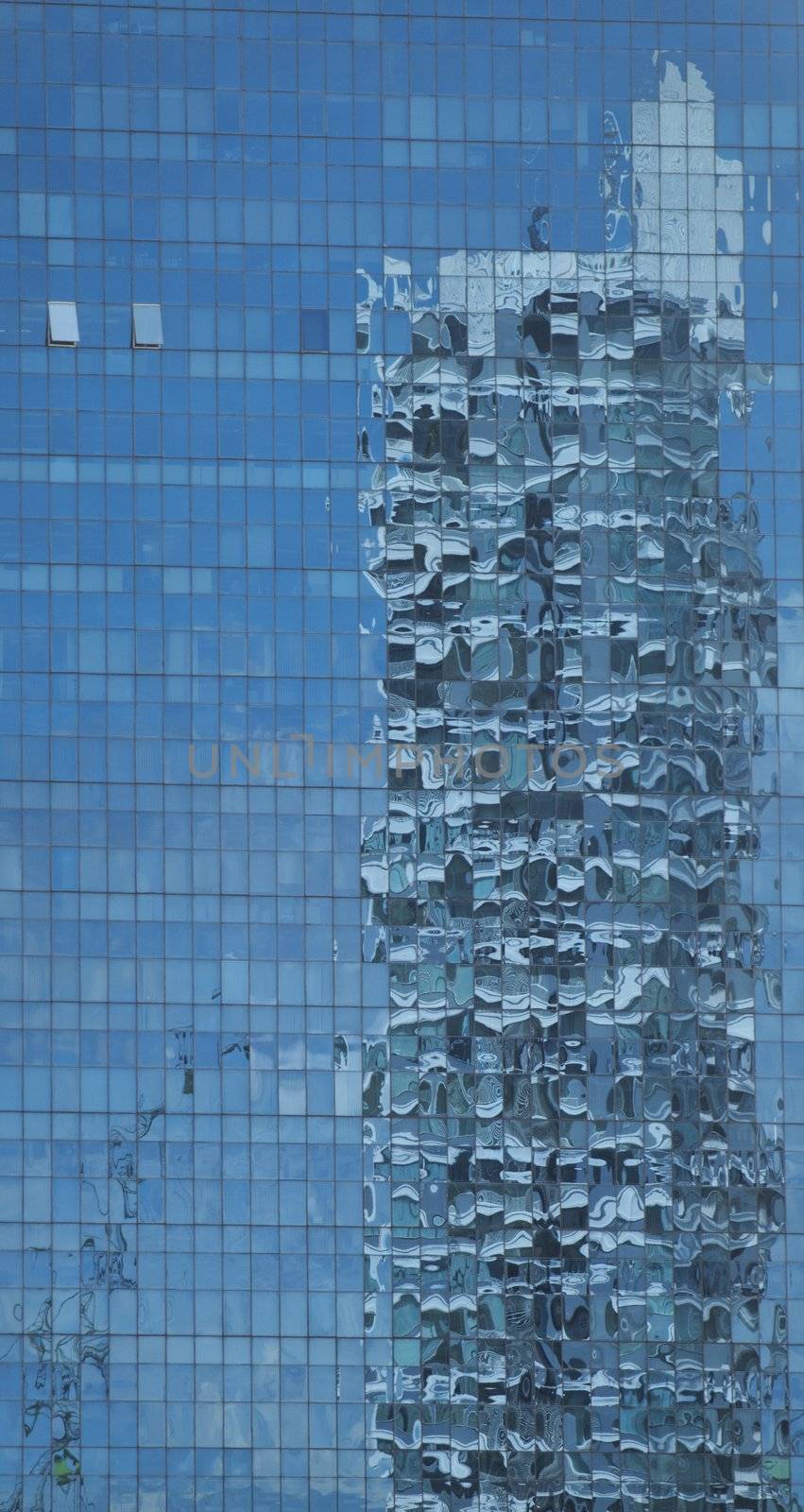 Panoramic view of skyscaper reflection on a blue glass building