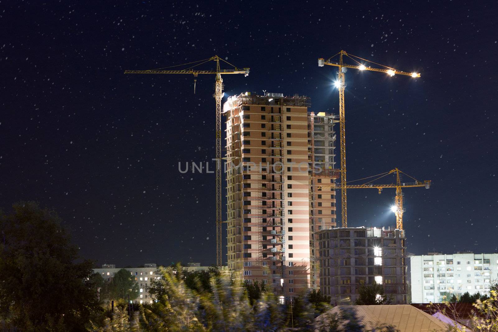 Construction Site at night with construction cranes.