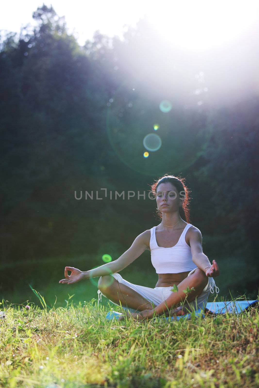 yoga woman on green grass lotus pose in sunrise light