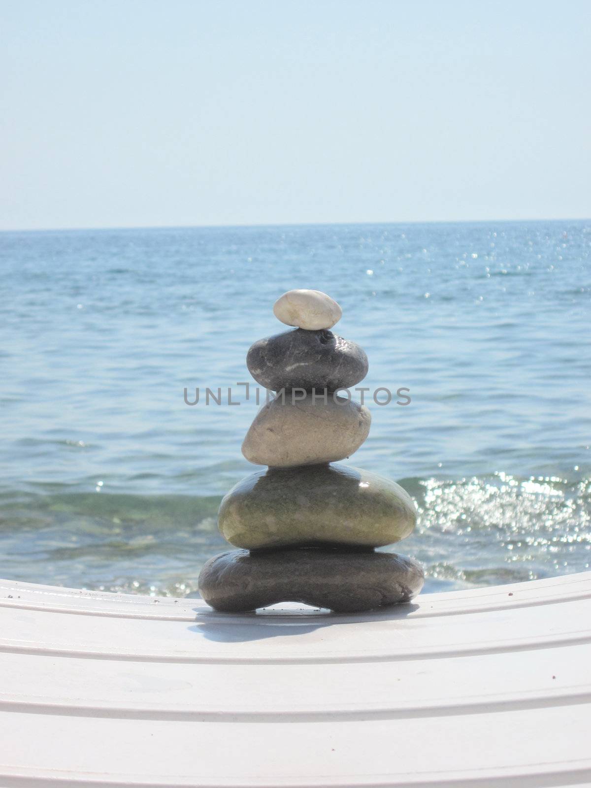 The stack of pebble stones in zen concept  on chaise longues 