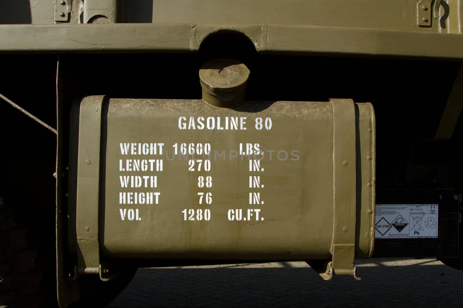 A vintage world war 2 vehicle gasoline tank with details written in white on olive green.