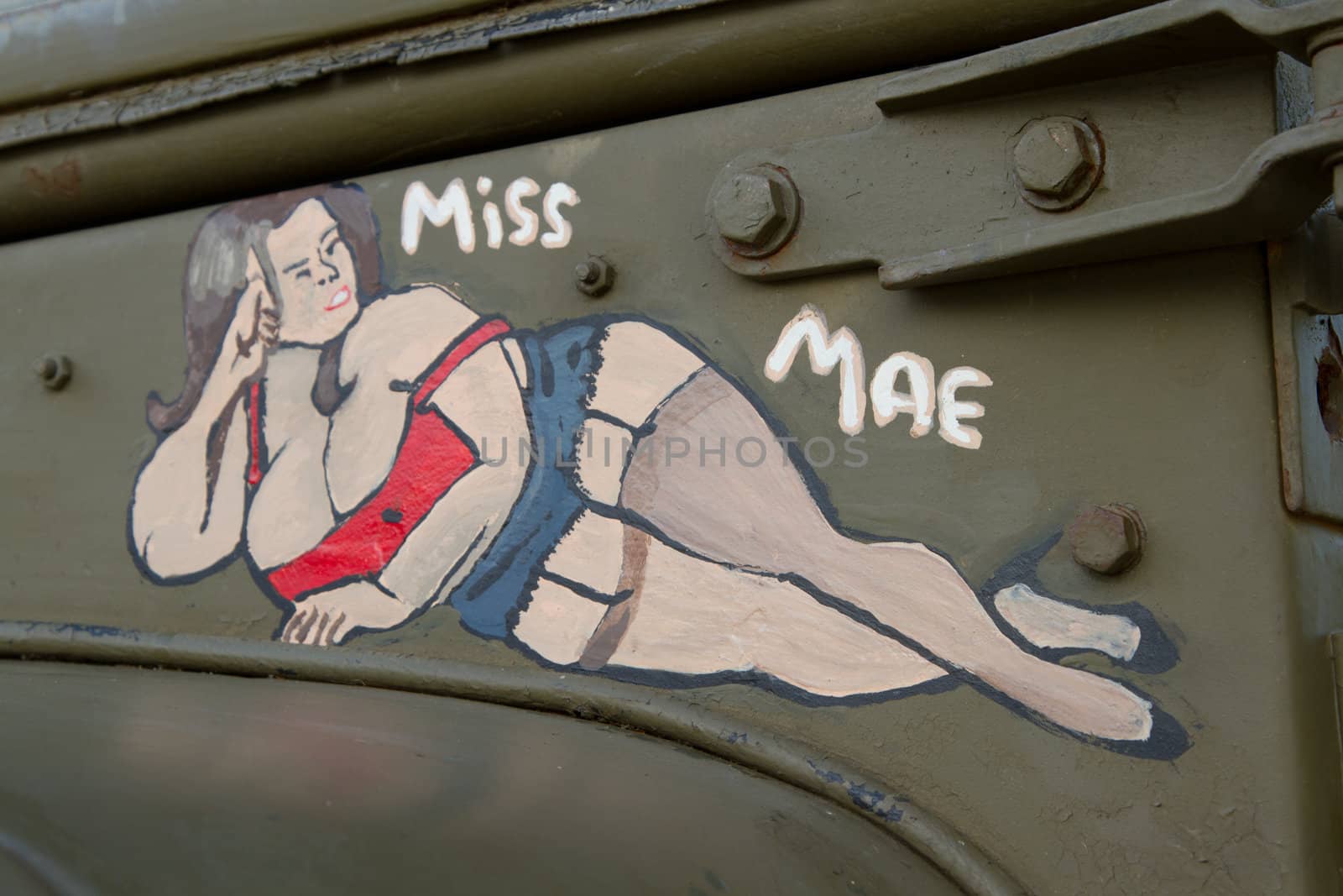 An historic American world war 2 artwork of a buxom woman hand painted onto the olive green surface of a vehicle.