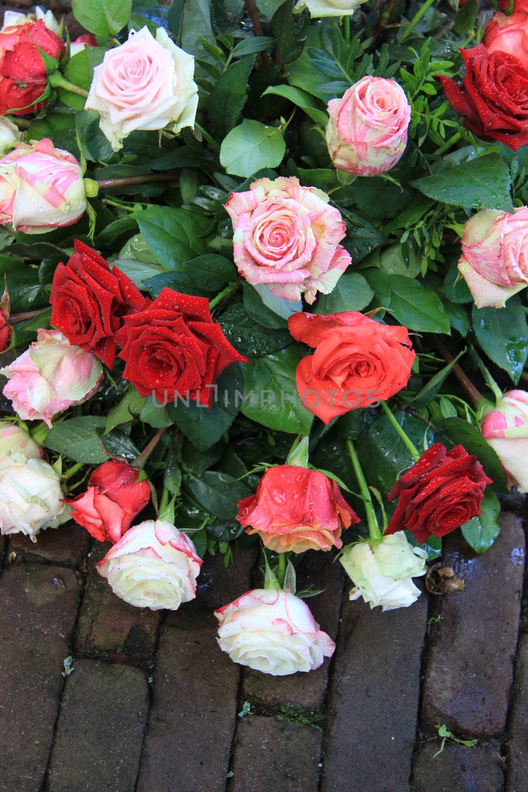 Wet sympathy flower bouquet on the pavement, mixed roses