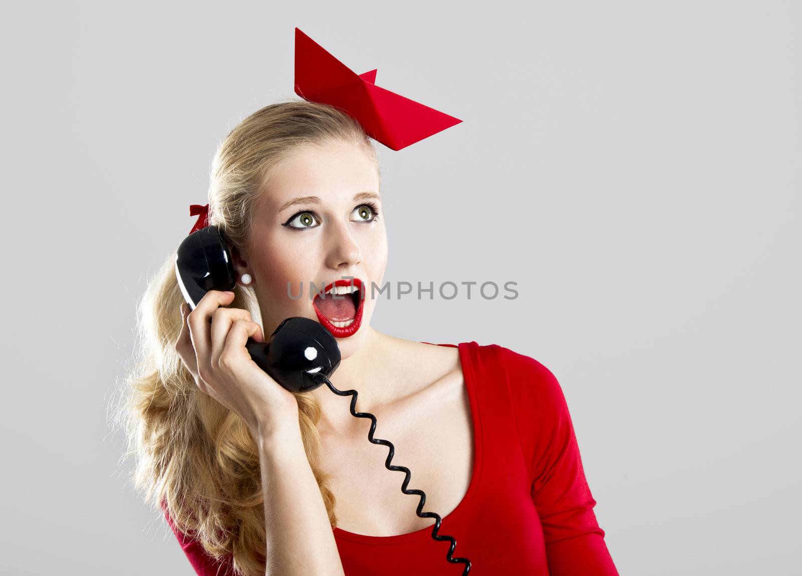 Beautiful fashion woman with a astonished expresion and holding a  vintage phone