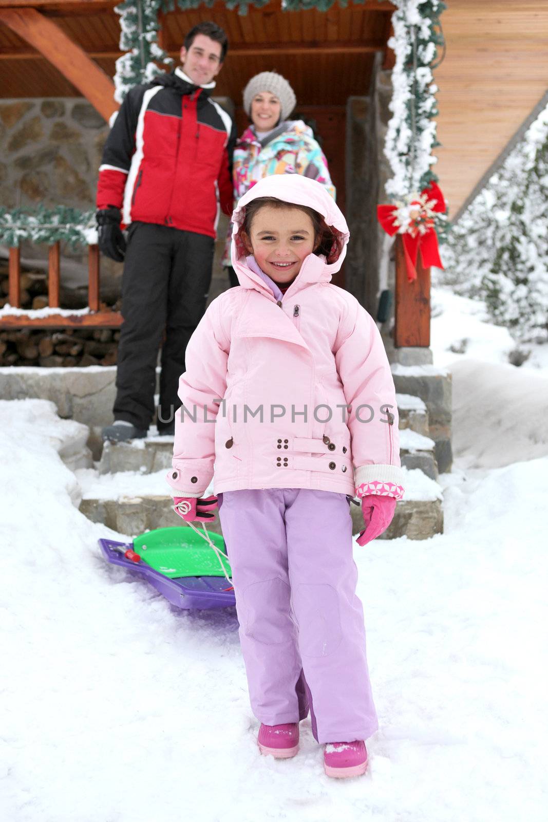 couple posing with daughter near chalet at ski resort
