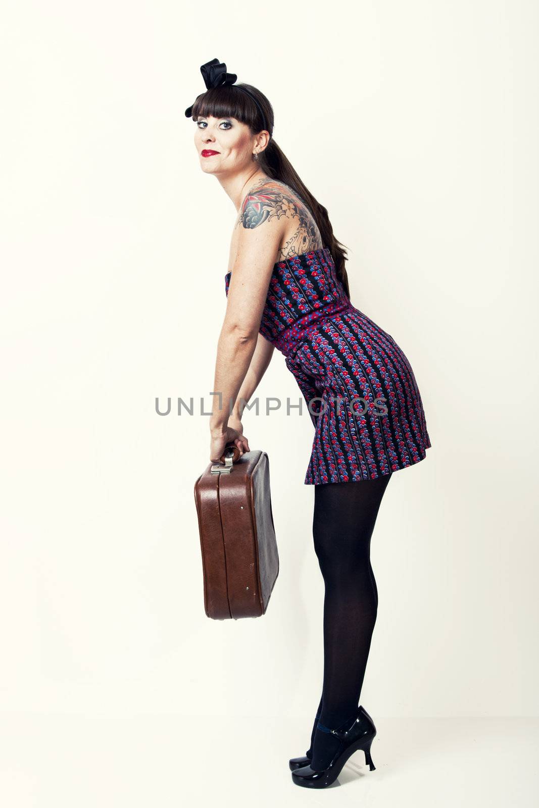 Portrait of a beautiful woman with a vintage look posing with a suitcase