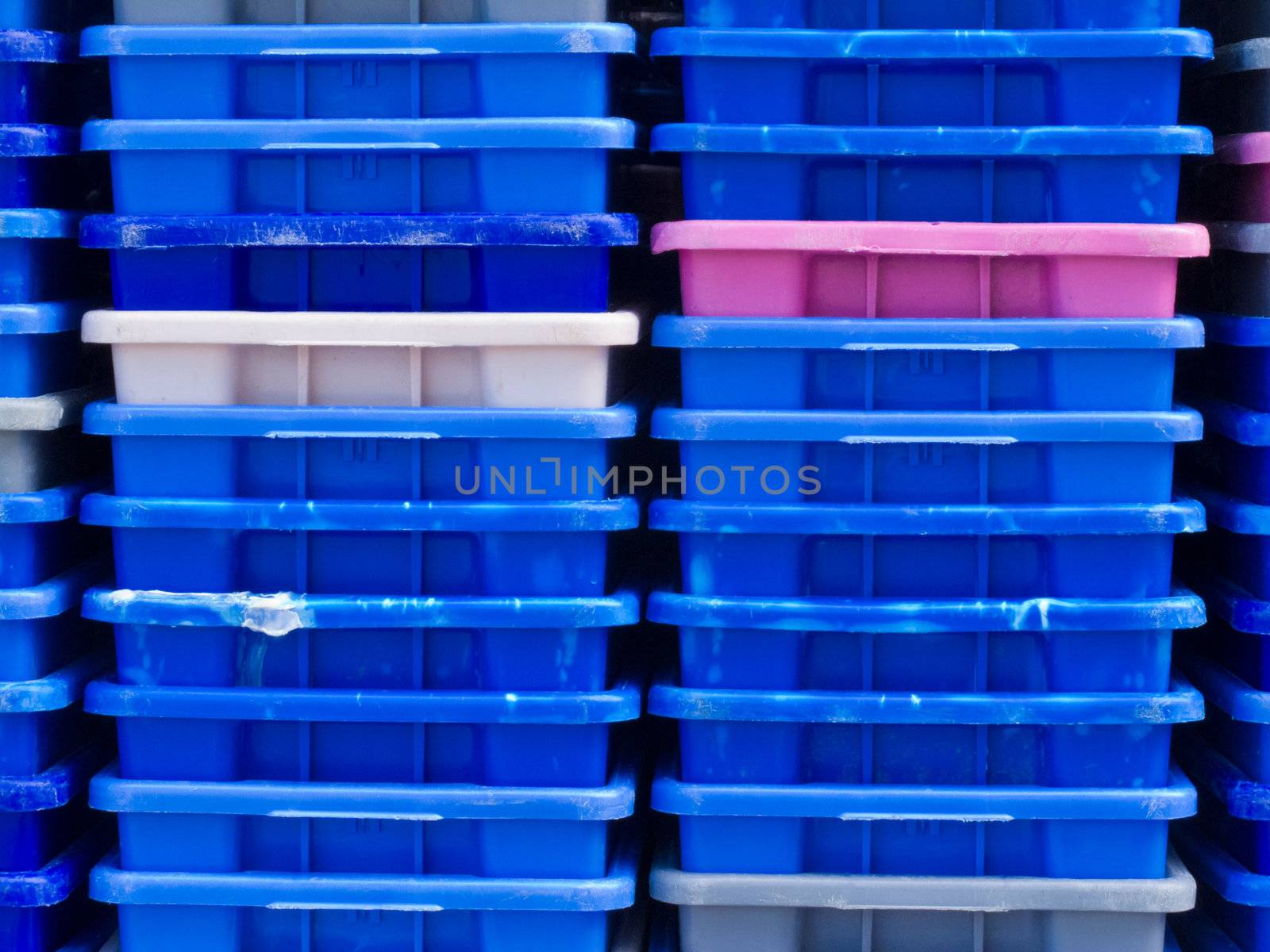 Background texture pattern of stacks of empty colorful plastic containers as used in fishery, wholesale, storage of fresh produce, cargo and retail transportation