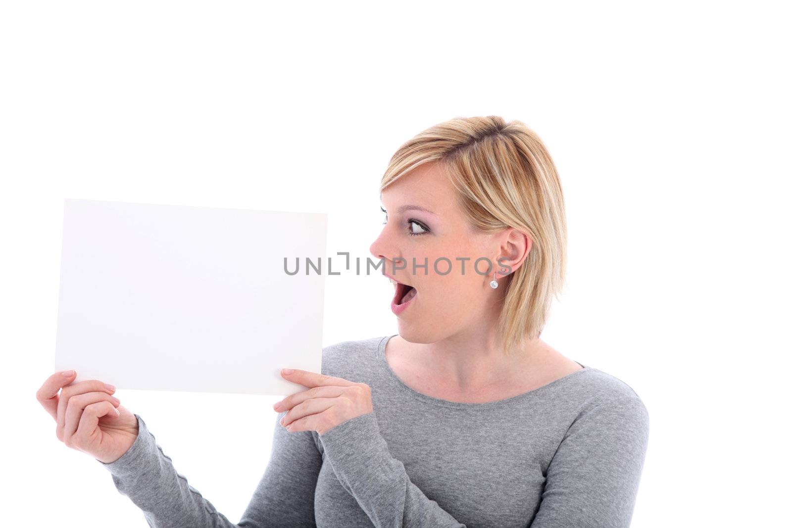 Woman with her mouth open in surprise looking at a blank sign that she is holding up to her side 